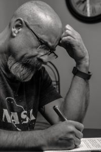 black and white photo of man with hand on his head thinking