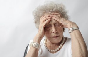 elderly woman holding her head like brain hurts